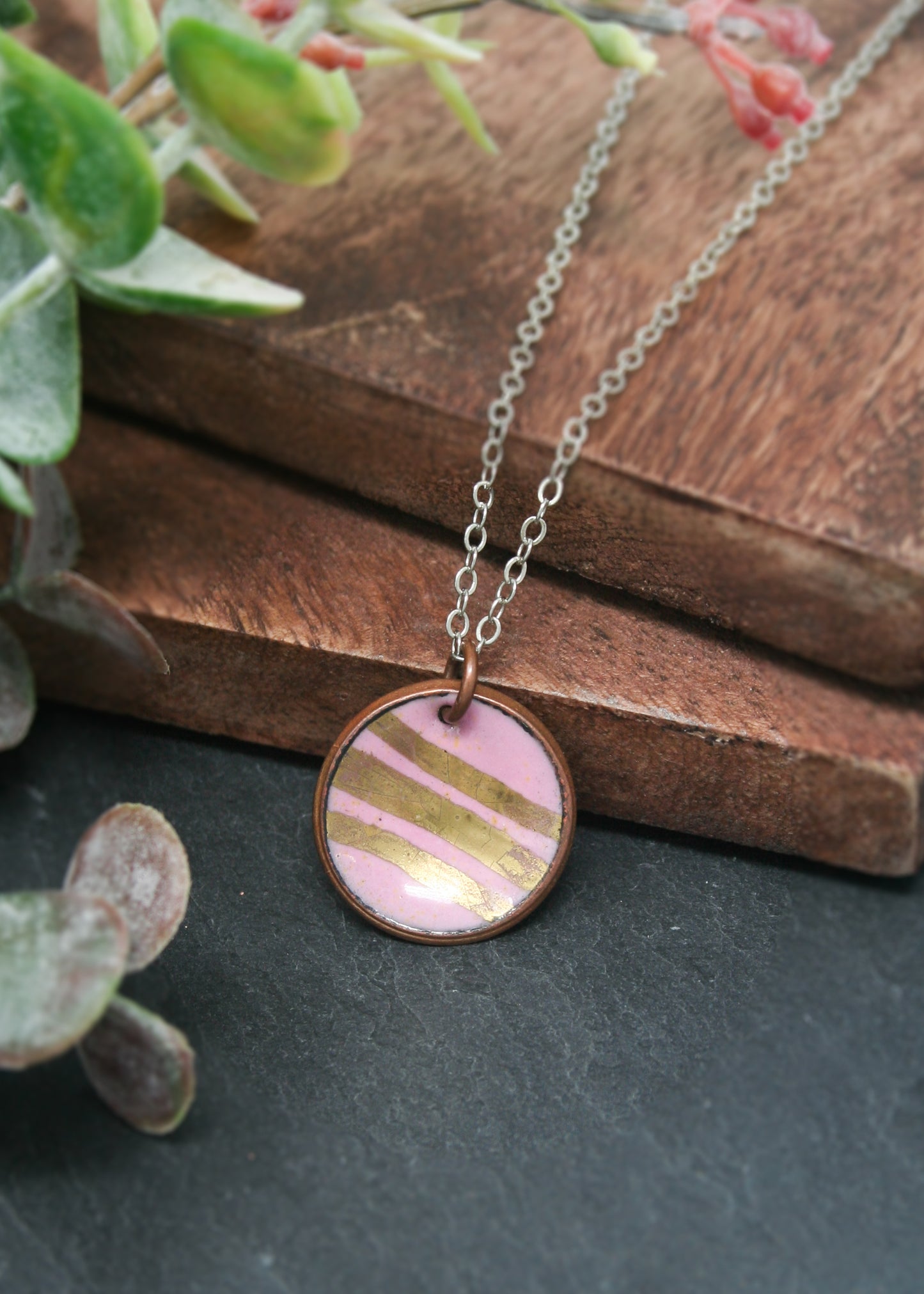a pink and gold necklace on a wooden table