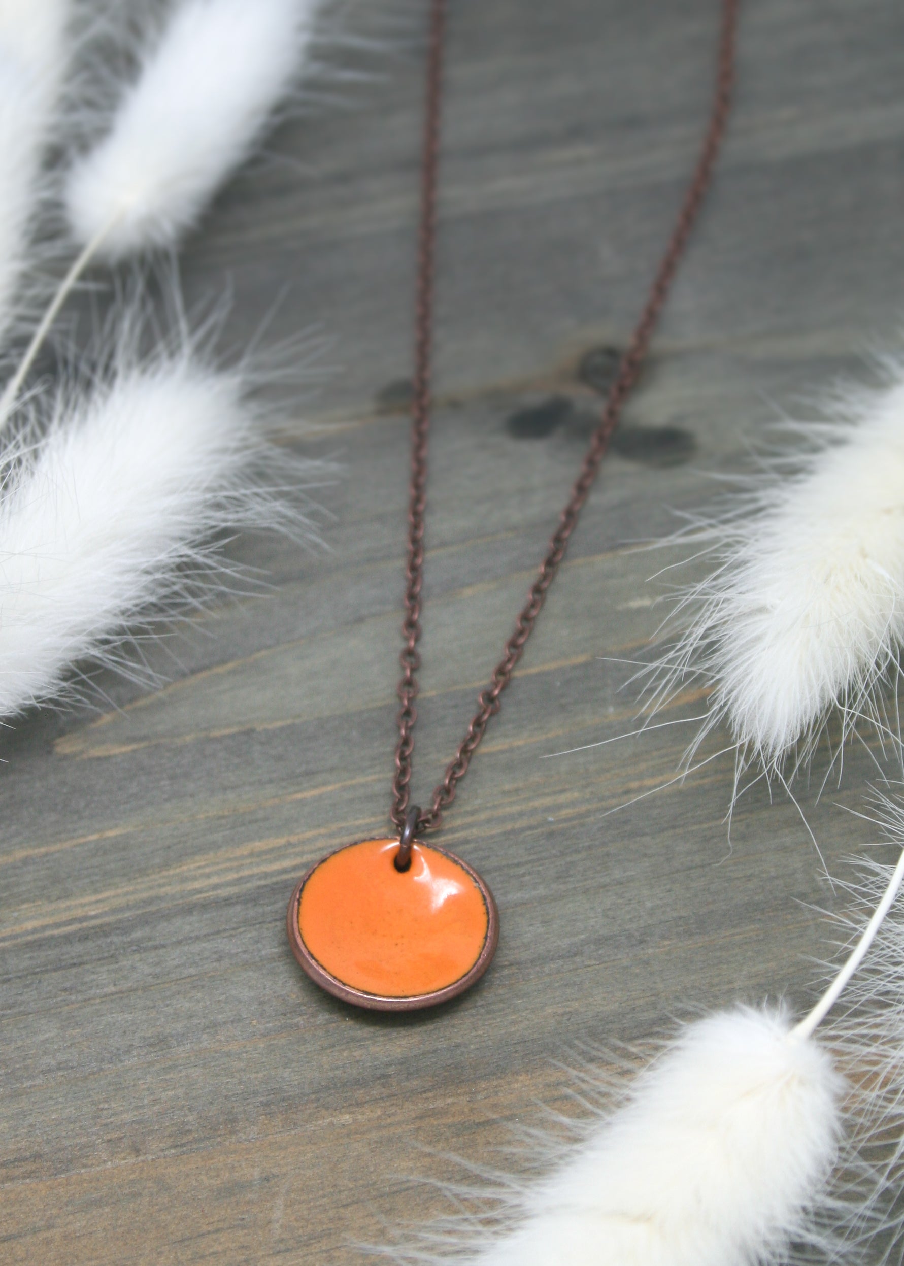 a necklace with an orange disc hanging from a chain