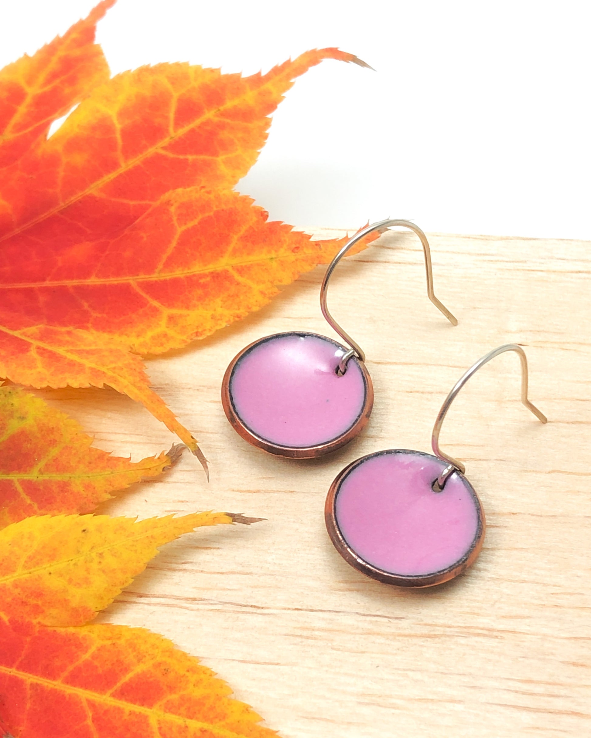 a pair of pink earrings sitting on top of a wooden table