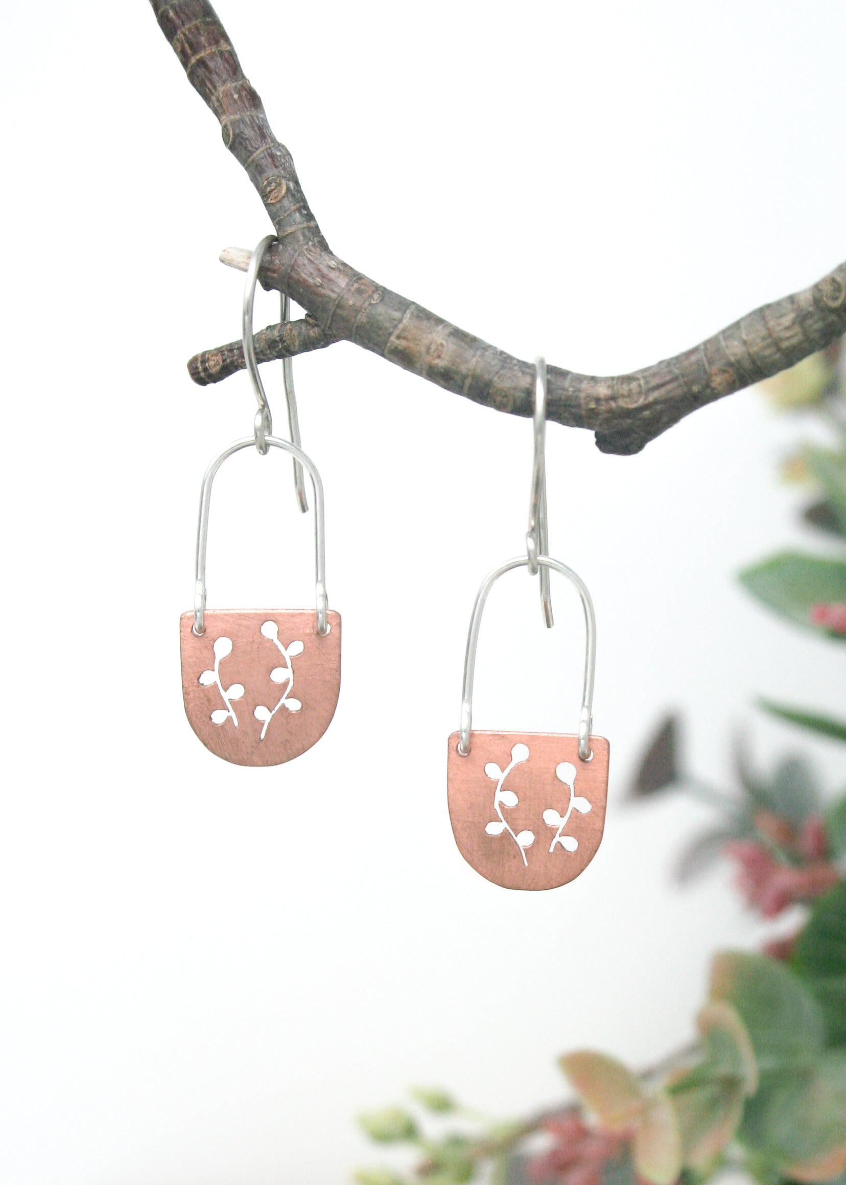 a pair of earrings hanging from a tree branch