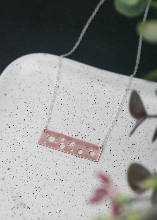 a necklace with three holes on it sitting on a plate