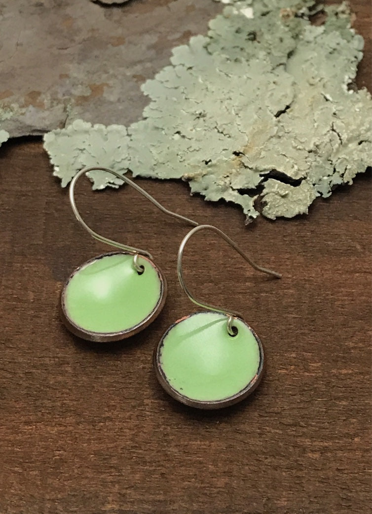 a pair of green earrings sitting on top of a wooden table