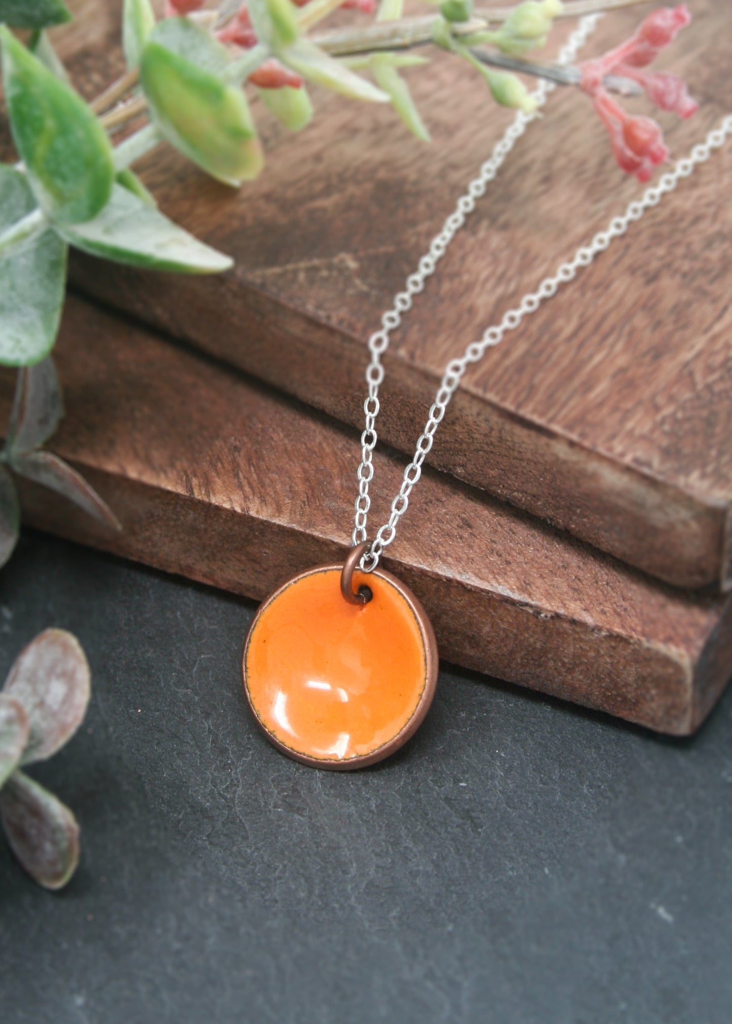 a necklace with an orange disc on it