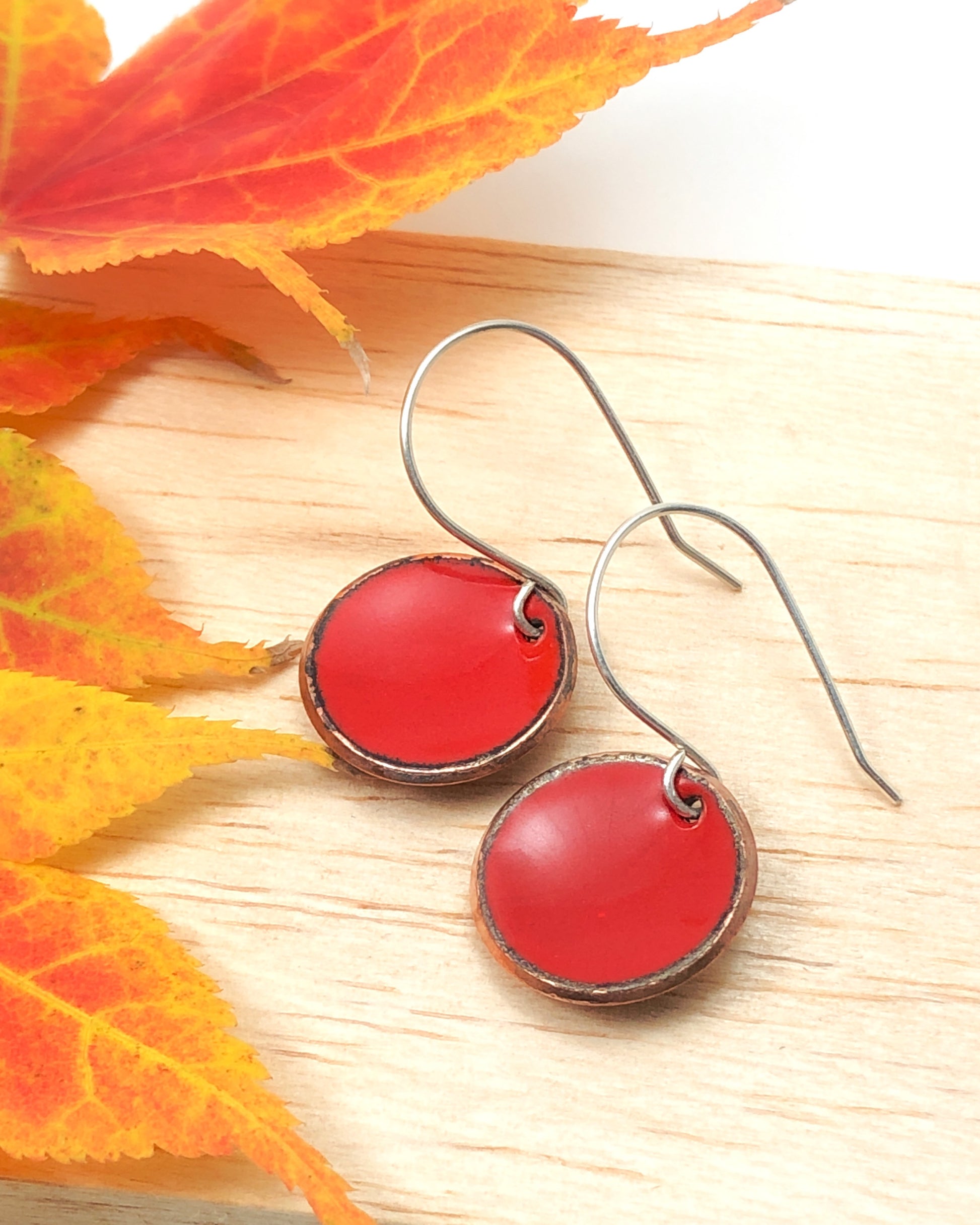 a pair of red earrings sitting on top of a wooden table