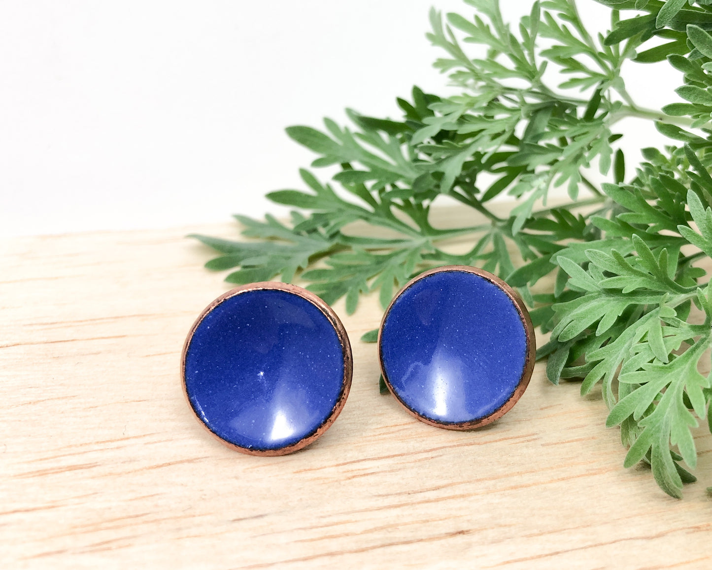 a pair of blue earrings sitting on top of a wooden table