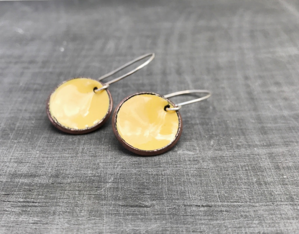 a pair of yellow earrings on a gray surface