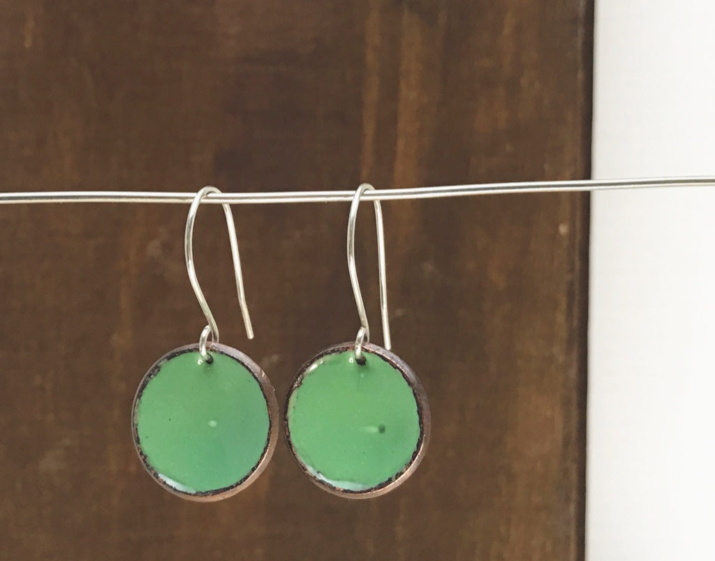 a pair of green earrings hanging from a clothes line