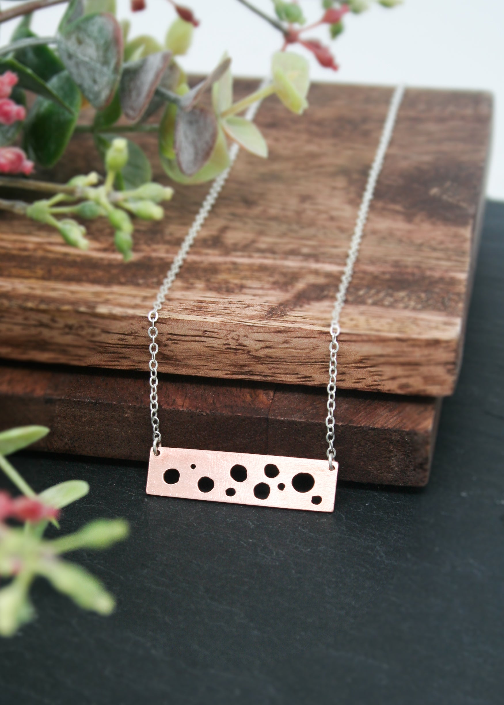 a silver necklace with black dots on it
