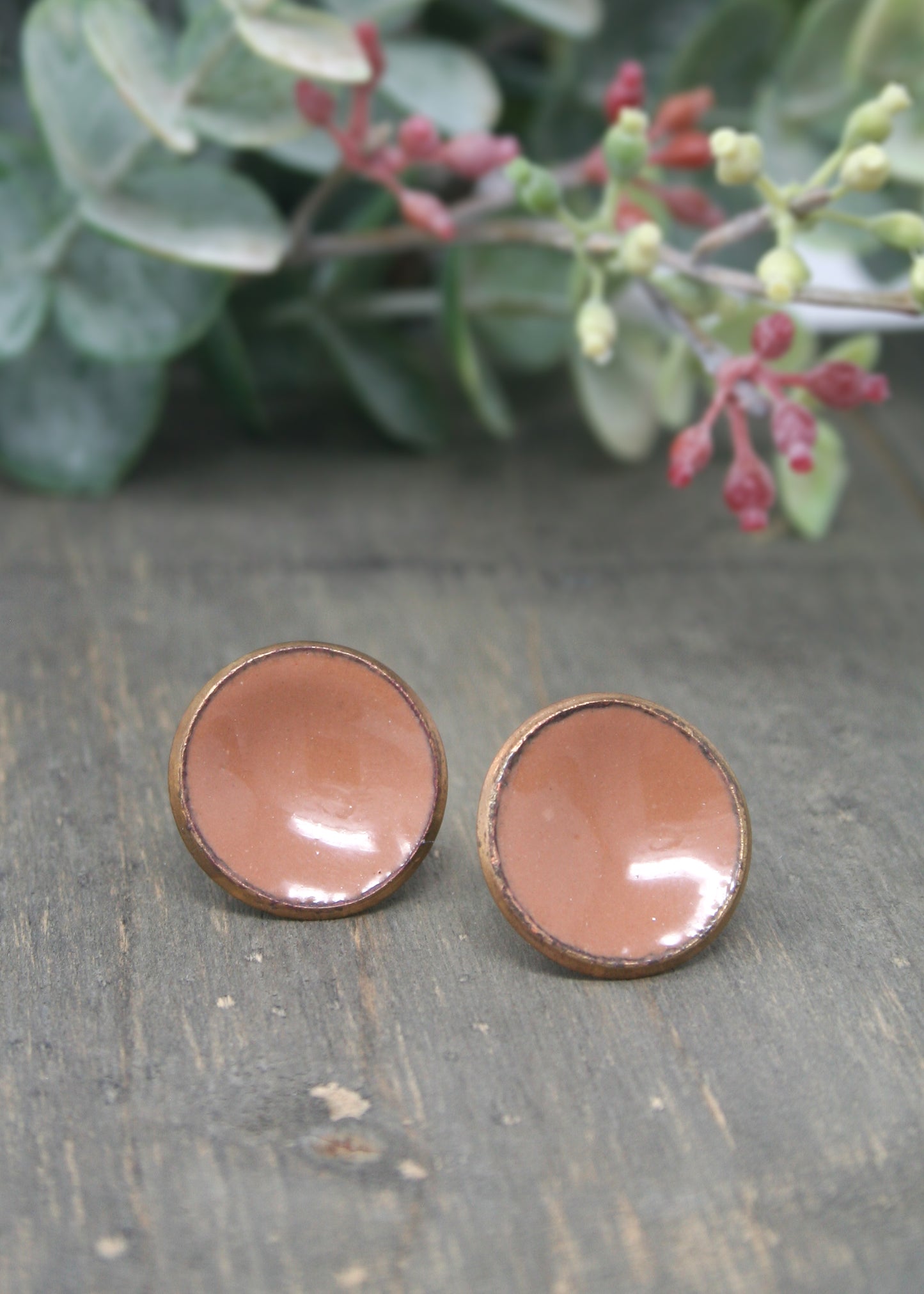 a pair of brown earrings sitting on top of a wooden table