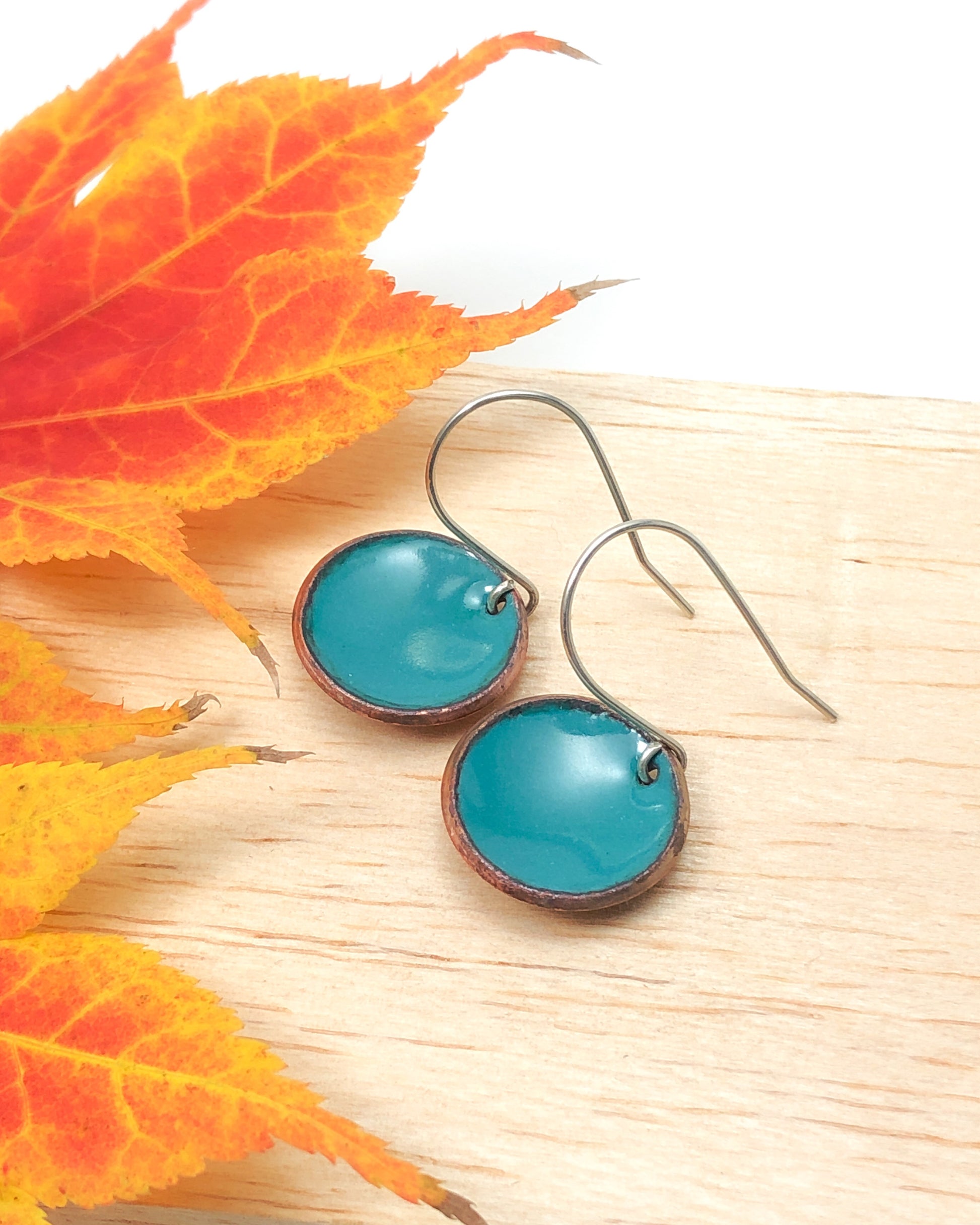 a pair of blue earrings sitting on top of a wooden table