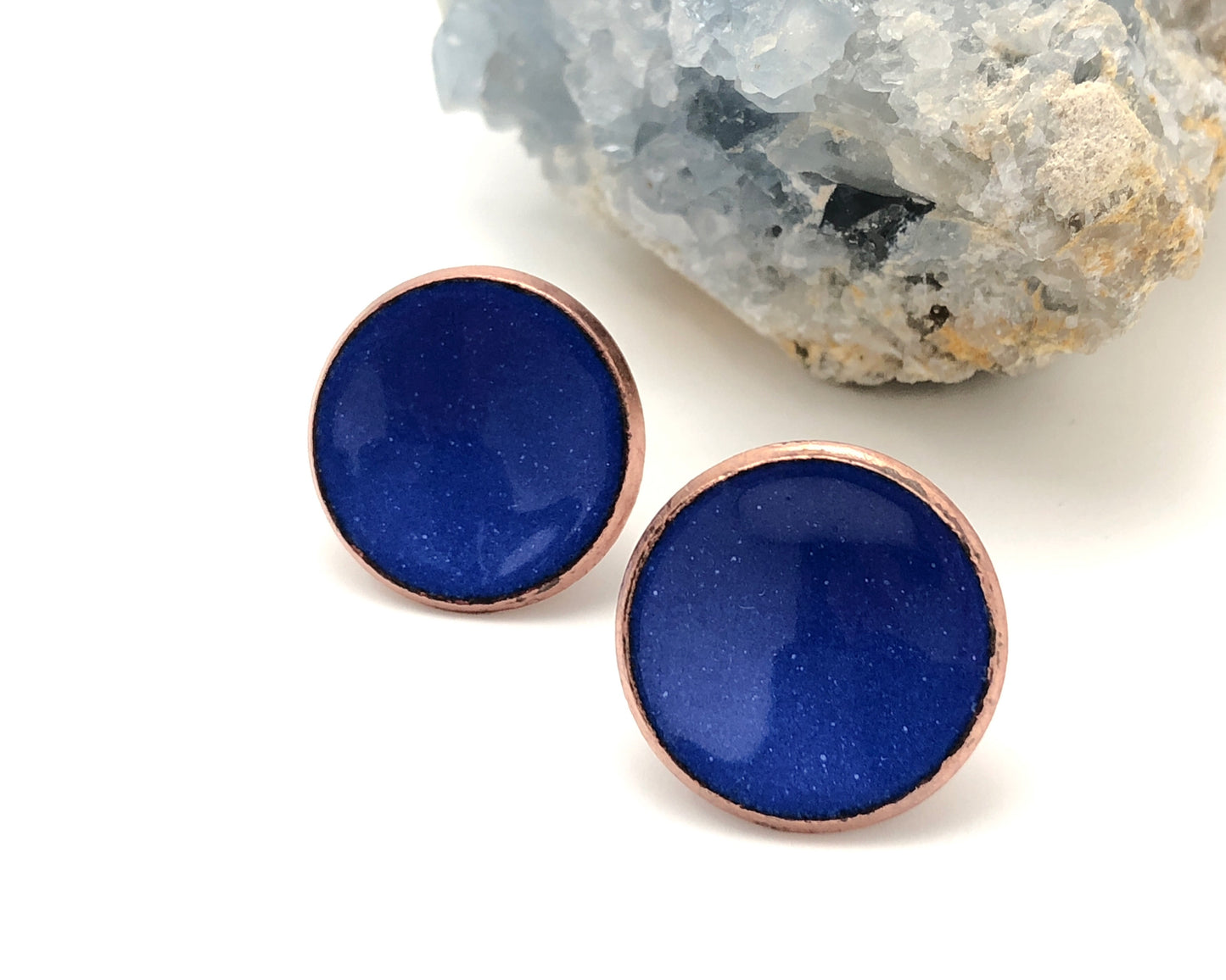 a pair of blue earrings sitting on top of a rock