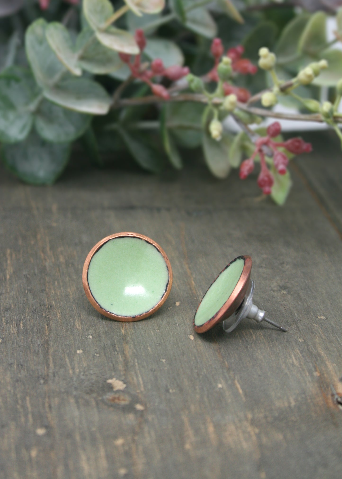 a pair of green earrings sitting on top of a wooden table