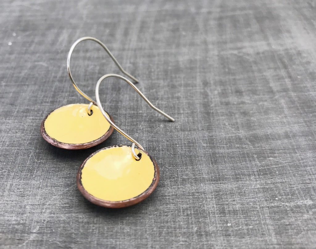 a pair of yellow earrings sitting on top of a table