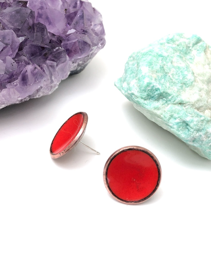 a pair of red earrings sitting next to a rock
