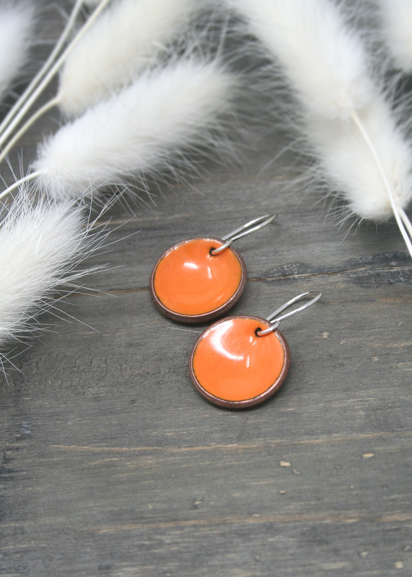 a pair of orange earrings sitting on top of a wooden table