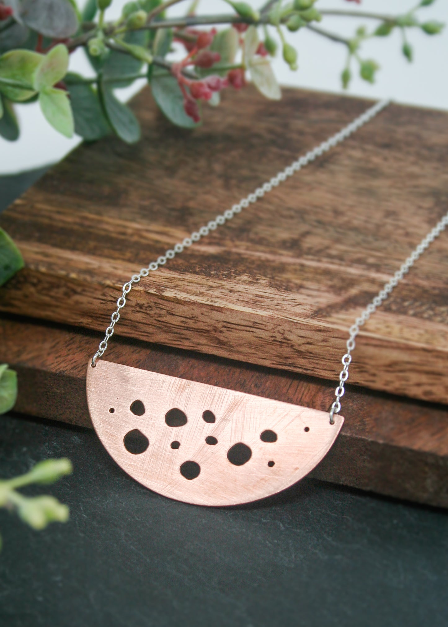 a metal necklace with holes in the middle of it